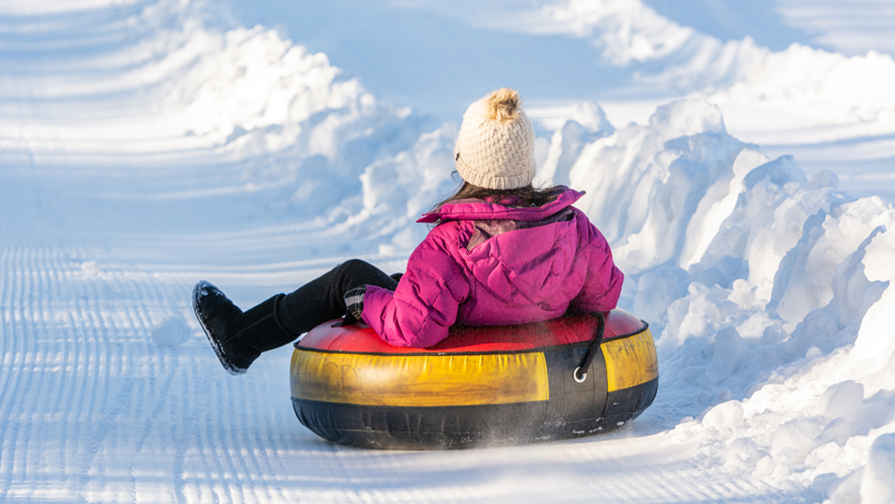 Enfant faisant du tube sur une butte de glisse enneigée