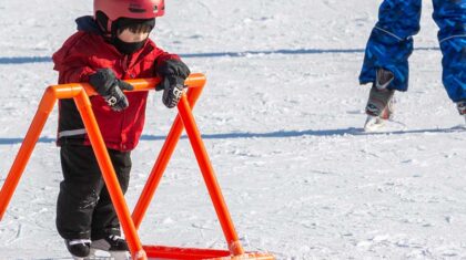 Enfant qui patine avec une barre d'apprentissage pour le patin
