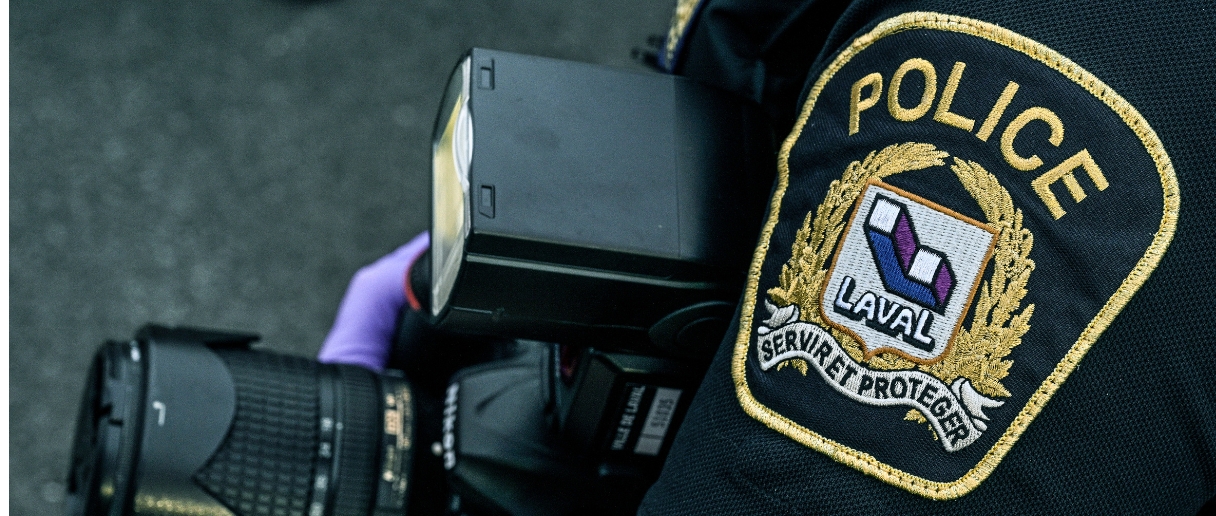 Une main de policier tient un appareil photo.