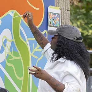 Artiste de l'organisme Mu qui peint la murale