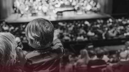 Un enfant dans les bras de sa mère regarde la scène.