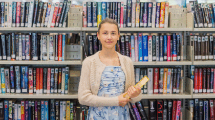Une fille avec un livre dans les mains devant des livres dans une bibliothèque