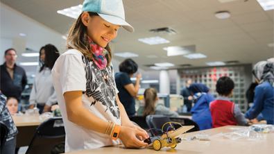Une ado qui construit un mini-robot lors du Festival NUM des bibliothèques.