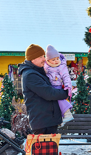 Une personne portant un ou une enfant dans ses bras au Marché de Noël de Laval au centre de la Nature