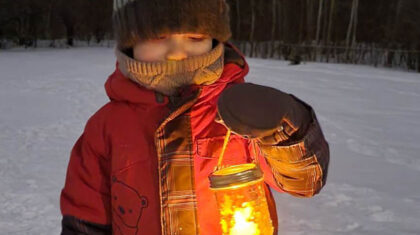 Un ou une enfant qui tient une lanterne dans ses mains l'hiver