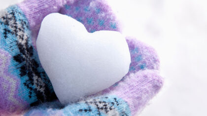 Une personne qui tient de la neige en forme de cœur dans ses mitaines