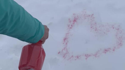 Quelqu'un qui fait un coeur dans la neige avec de la peinture en aérosol