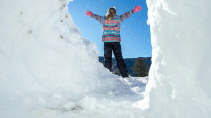 Une jeune fille debout, de dos, dans la neige
