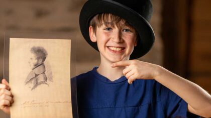 Enfant avec un chapeau haut de forme qui tient un dessin avec un portrait