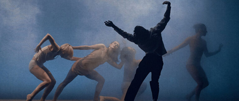 Spectacle de danse La revue finale | Sur une scène de danse baignée d’une lumière bleutée et brumeuse, plusieurs personnes exécutent une composition chorégraphique. Les corps sont penchés ou étirés dans différentes directions, avec des bras levés et des torses inclinés.