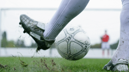 Une personne qui joue avec un ballon de soccer blanc sur un terrain de soccer extérieur