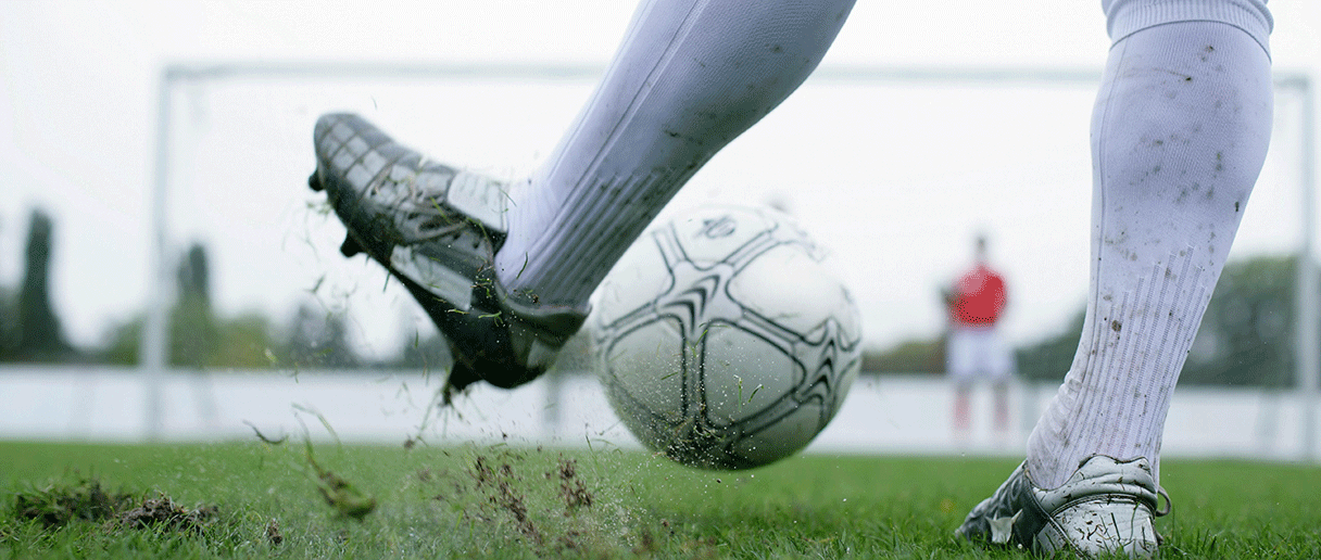 Une personne qui joue avec un ballon de soccer blanc sur un terrain de soccer extérieur
