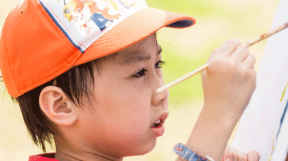 Un enfant qui fait de la peinture sur une toile dans un parc