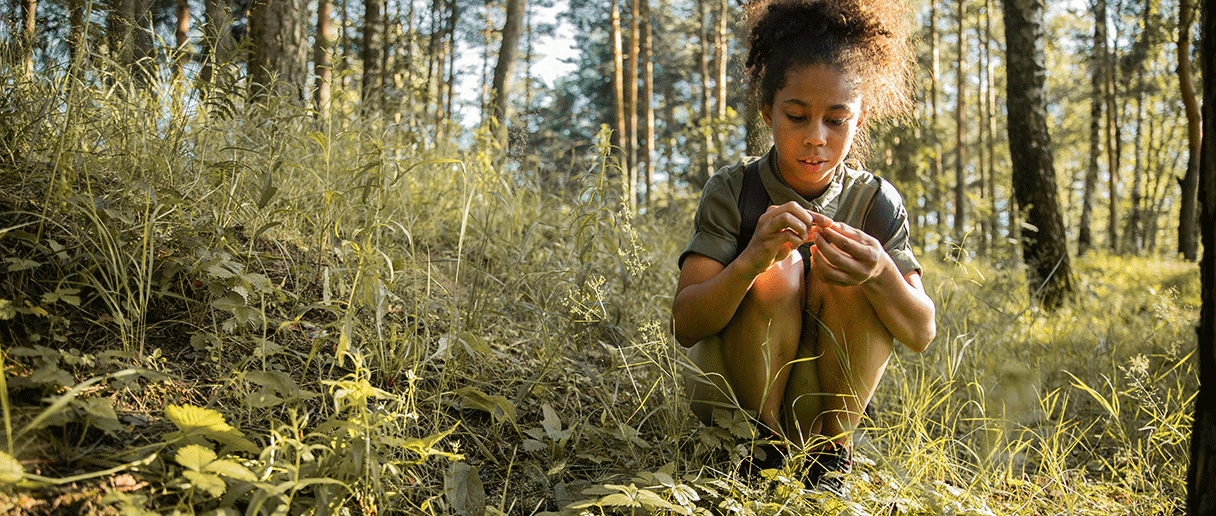 Enfant explorant la nature (herbes, fleurs)
