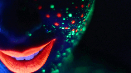 une personne avec du maquillage fluo dans le noir.