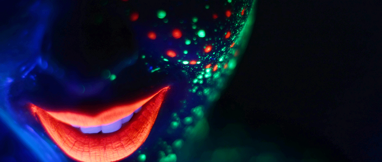 une personne avec du maquillage fluo dans le noir.
