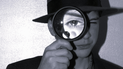 Un enfant qui tient une loupe devant son oeil