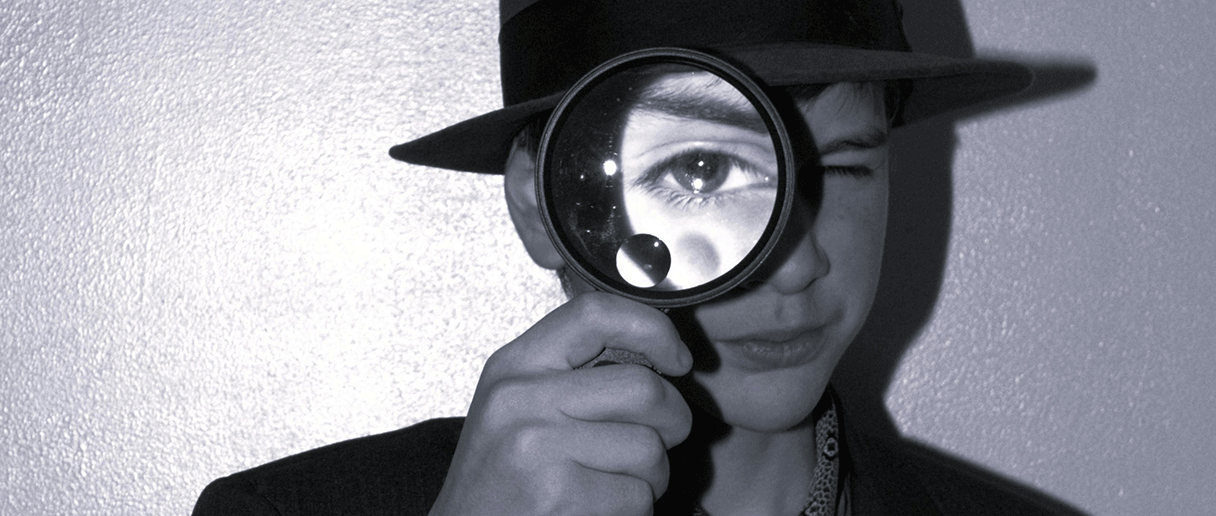 Un enfant qui tient une loupe devant son oeil