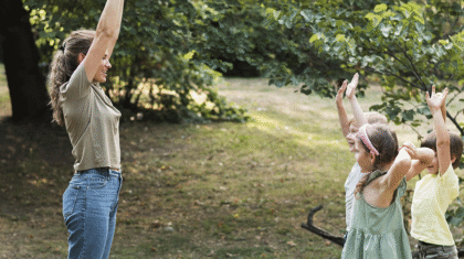 Une adulte et des enfants faisant de la Zumba dans un parc