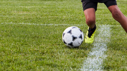 Une personne qui joue avec un ballon de soccer sur un terrain extérieur