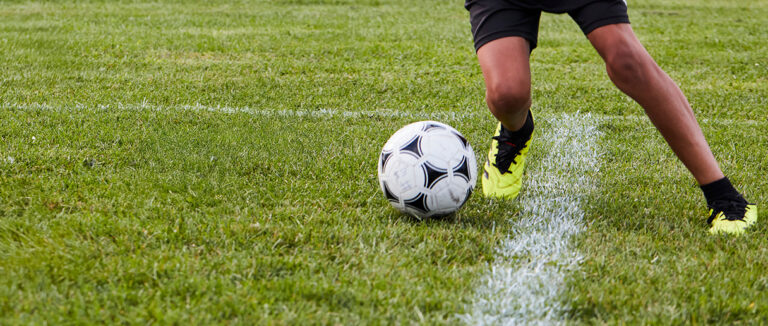 Une personne qui joue avec un ballon de soccer sur un terrain extérieur