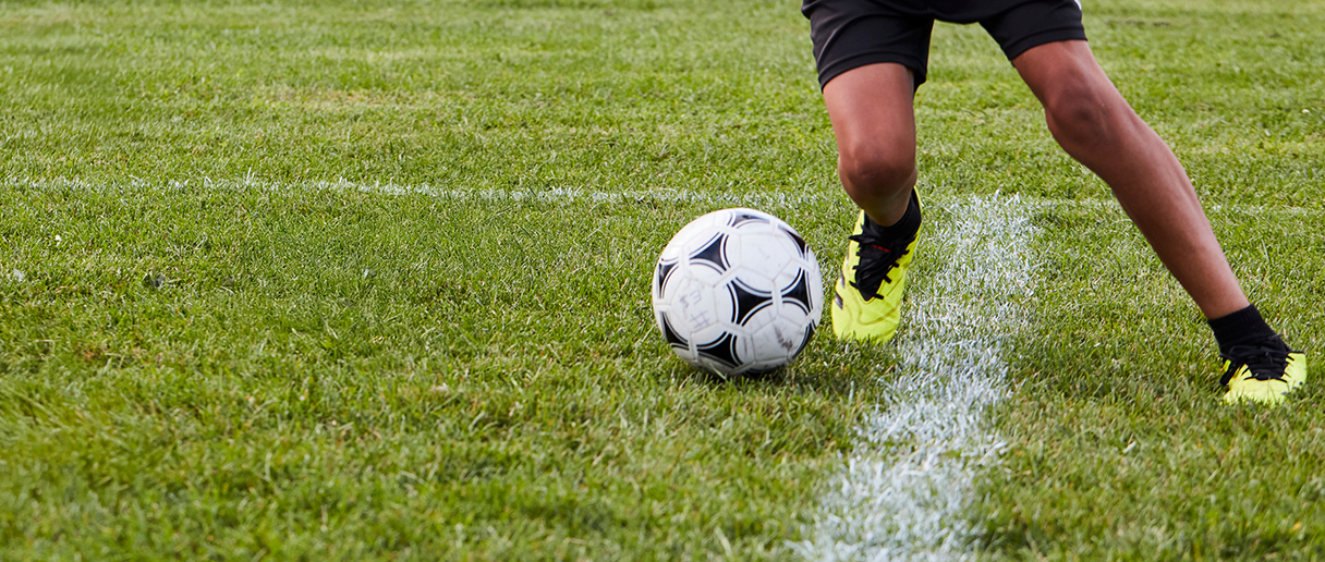 Une personne qui joue avec un ballon de soccer sur un terrain extérieur